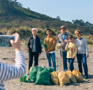 Girl taking photo to group of volunteers after cleaning beach