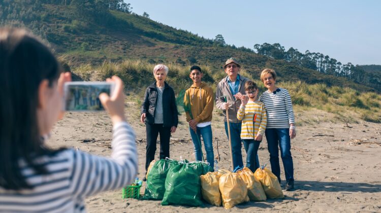 Girl taking photo to group of volunteers after cleaning beach